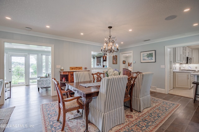 dining area featuring light hardwood / wood-style floors, a notable chandelier, ornamental molding, and a textured ceiling