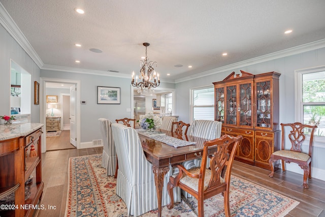 dining space featuring crown molding, a textured ceiling, visible vents, and wood finished floors