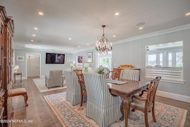 dining area with a notable chandelier, crown molding, a textured ceiling, and light hardwood / wood-style floors