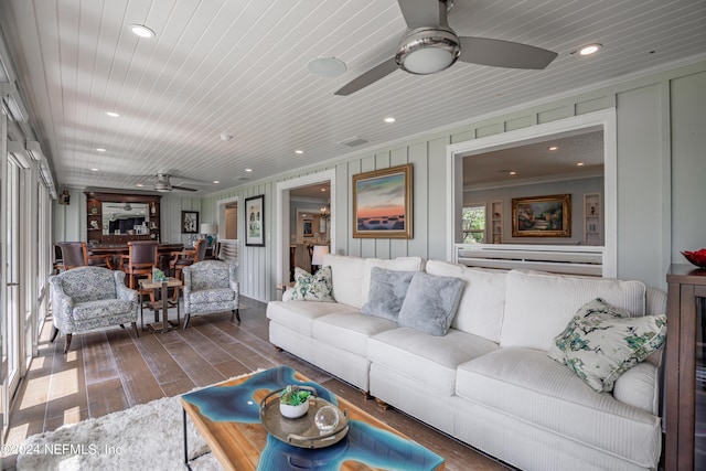 living area with wood ceiling, ceiling fan, ornamental molding, dark wood-style flooring, and a decorative wall