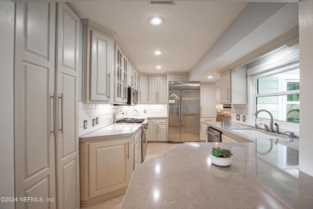 kitchen with sink, tasteful backsplash, a textured ceiling, and high quality appliances