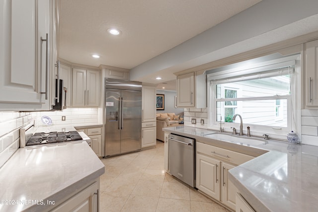 kitchen with sink, backsplash, appliances with stainless steel finishes, and light tile patterned floors