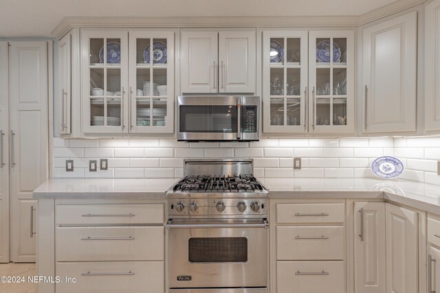 kitchen with appliances with stainless steel finishes, white cabinets, and backsplash