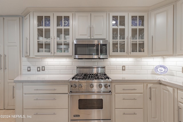 kitchen featuring stainless steel appliances, white cabinetry, and glass insert cabinets