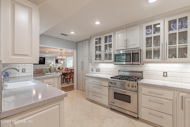 kitchen featuring glass insert cabinets, appliances with stainless steel finishes, light countertops, and a sink