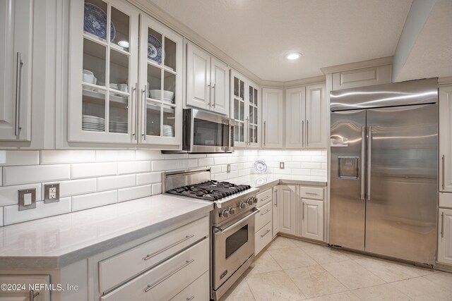 kitchen with light tile patterned floors, tasteful backsplash, and high end appliances