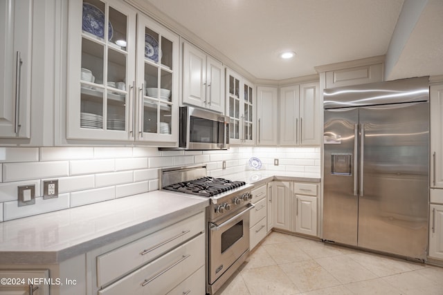 kitchen with light countertops, glass insert cabinets, backsplash, and high quality appliances