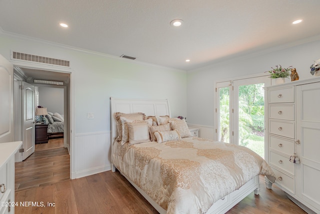 bedroom featuring dark wood-style floors, a wainscoted wall, visible vents, and access to exterior