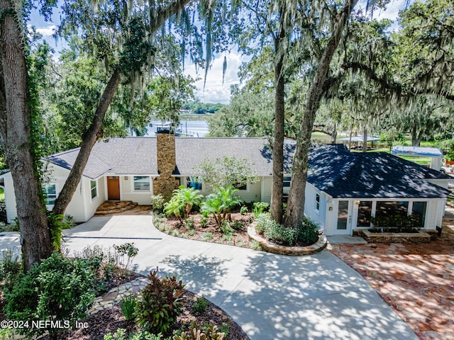 ranch-style home with concrete driveway, a shingled roof, and a chimney