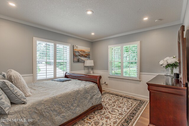 bedroom with crown molding, wood-type flooring, and a textured ceiling