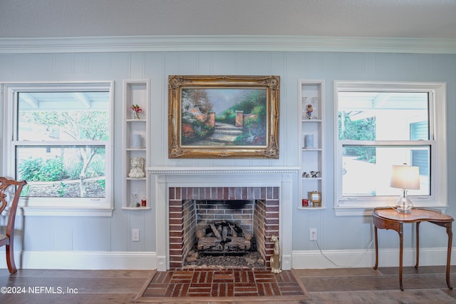 living room featuring a wealth of natural light, crown molding, wood-type flooring, and a brick fireplace