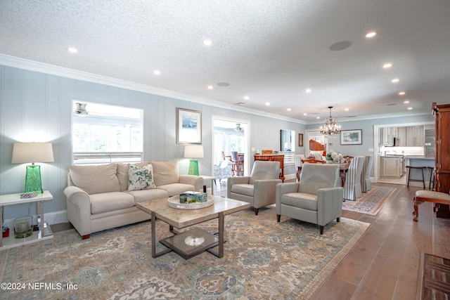 living room featuring dark hardwood / wood-style flooring, a textured ceiling, crown molding, and a chandelier