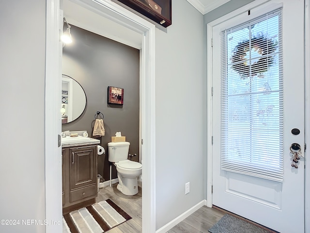 bathroom featuring wood-type flooring, ornamental molding, vanity, and toilet