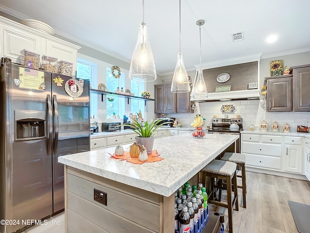 kitchen with dark brown cabinetry, light hardwood / wood-style flooring, appliances with stainless steel finishes, and a center island