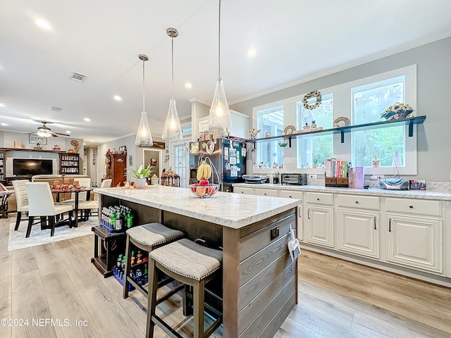 kitchen with white cabinetry, a kitchen island, light hardwood / wood-style flooring, ceiling fan, and stainless steel fridge