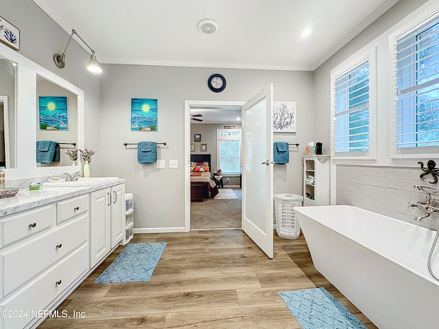 bathroom featuring wood-type flooring, a bathtub, backsplash, ornamental molding, and vanity