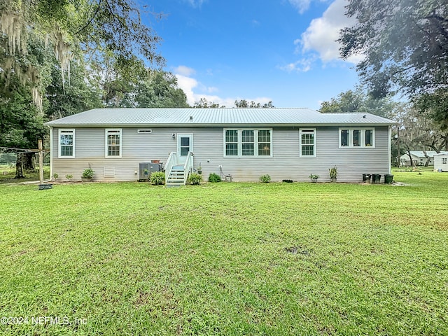 rear view of house featuring a lawn and central AC