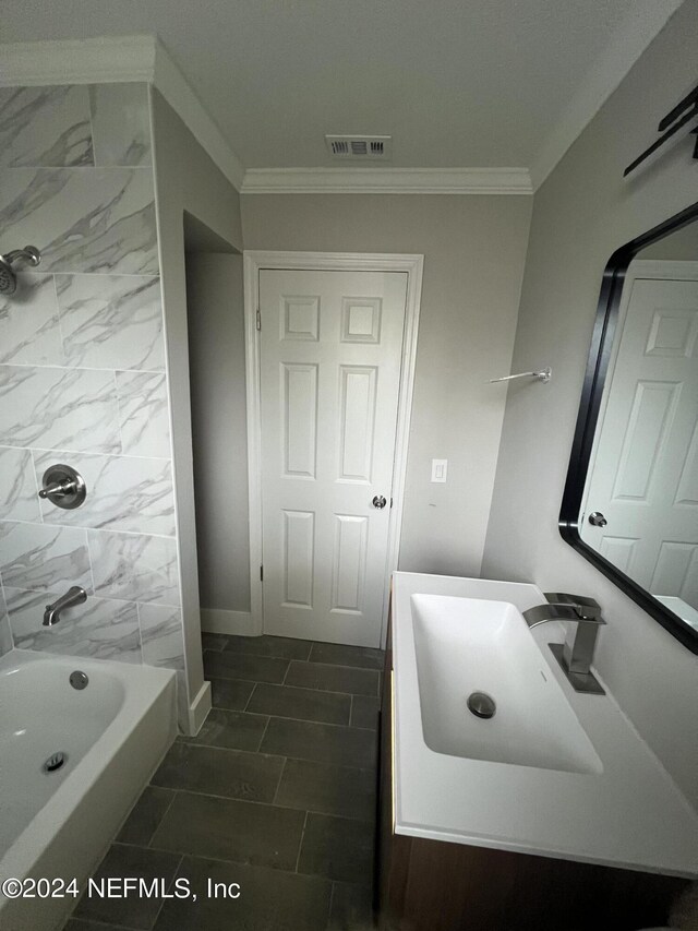 bathroom featuring tile patterned floors, crown molding, vanity, and tiled shower / bath