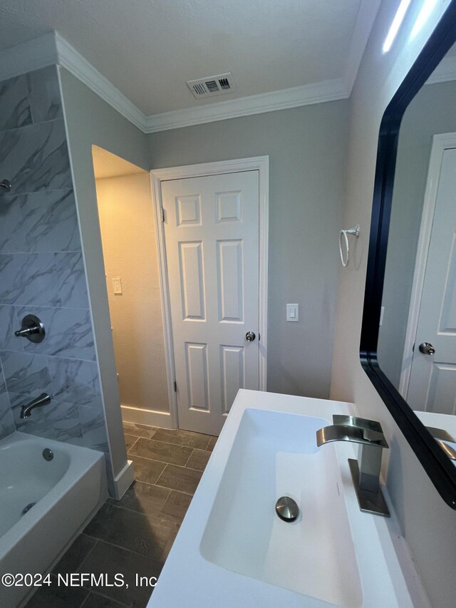 bathroom featuring crown molding, tiled shower / bath, tile patterned floors, and vanity