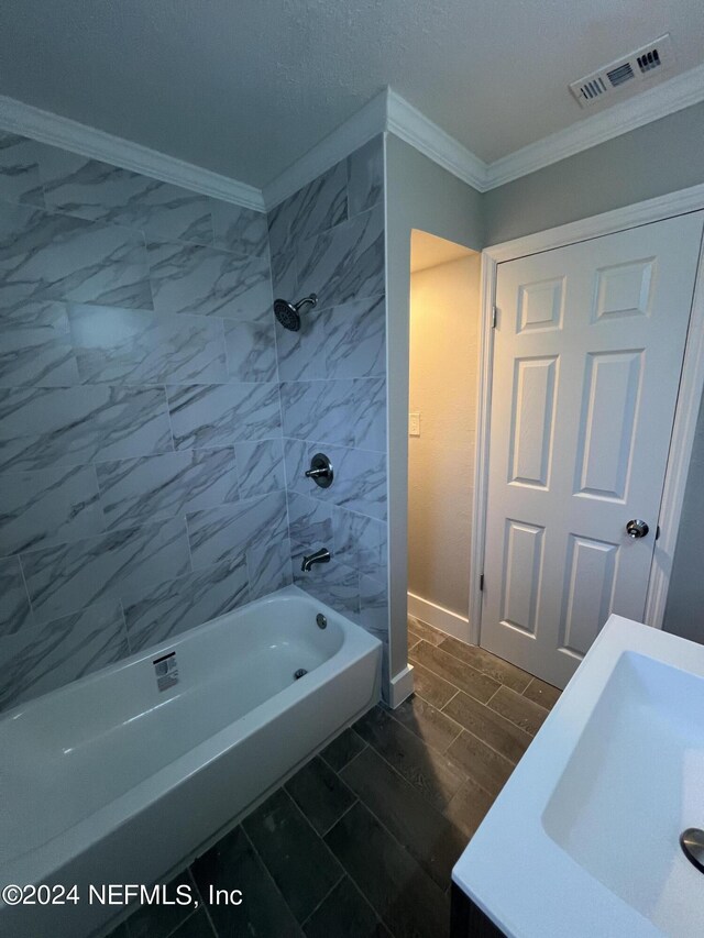 bathroom featuring a textured ceiling, ornamental molding, tiled shower / bath combo, and tile patterned floors