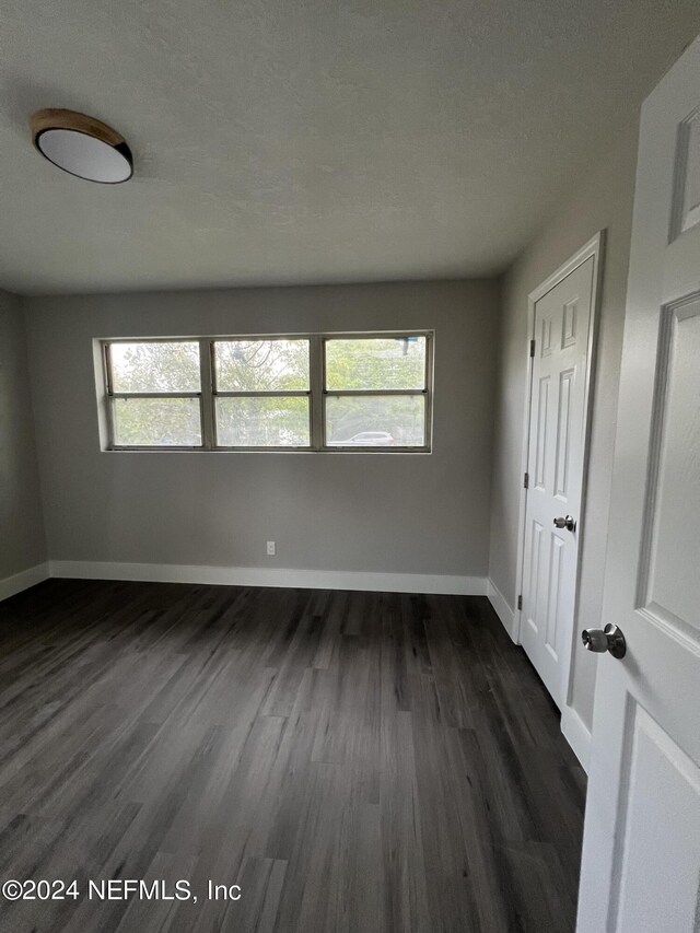 empty room featuring dark hardwood / wood-style floors and a textured ceiling