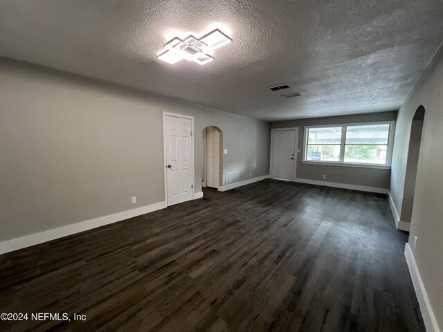 empty room with dark hardwood / wood-style floors and a textured ceiling