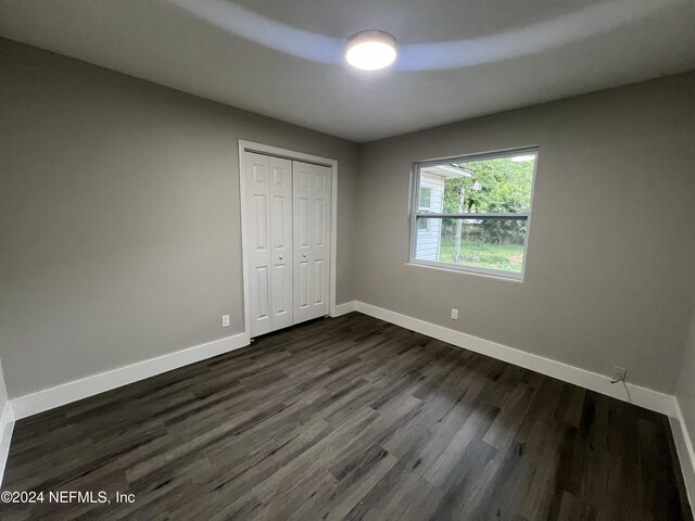 unfurnished bedroom featuring a closet and dark hardwood / wood-style flooring