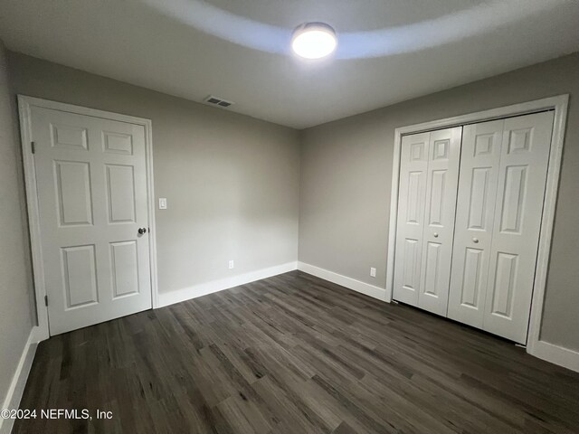 unfurnished bedroom with a closet and dark hardwood / wood-style floors