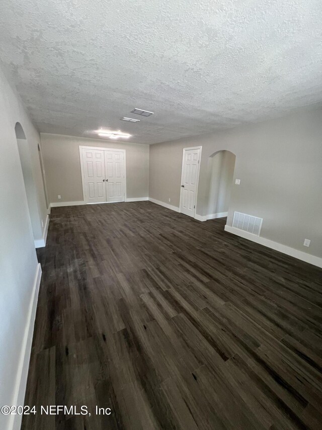 unfurnished living room featuring a textured ceiling and dark hardwood / wood-style floors