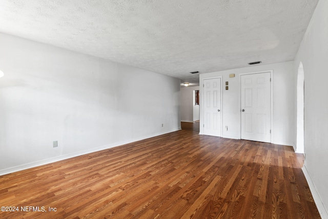 unfurnished bedroom with a textured ceiling, two closets, and hardwood / wood-style flooring