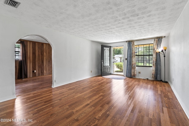 empty room with a textured ceiling and dark wood-type flooring