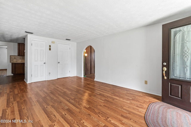 unfurnished living room with wood-type flooring and a textured ceiling