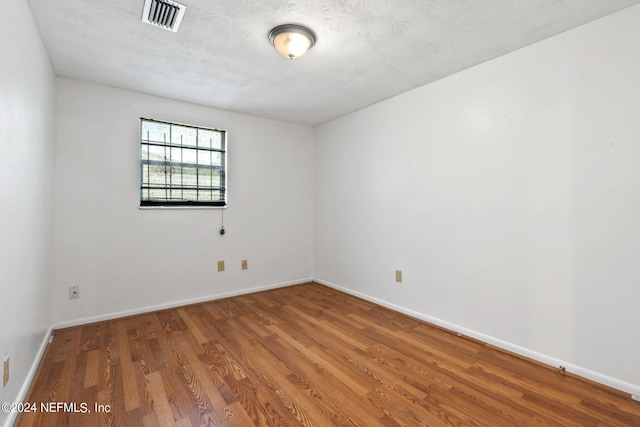 spare room featuring wood-type flooring and a textured ceiling