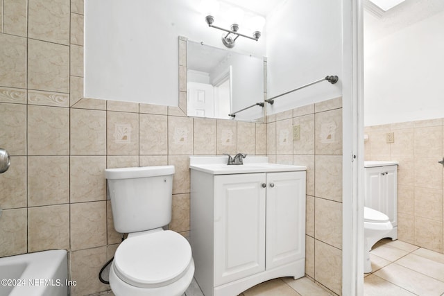 bathroom featuring toilet, a bathing tub, vanity, tile walls, and tile patterned floors