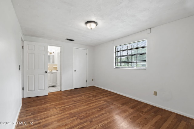 unfurnished bedroom with hardwood / wood-style floors and ensuite bathroom