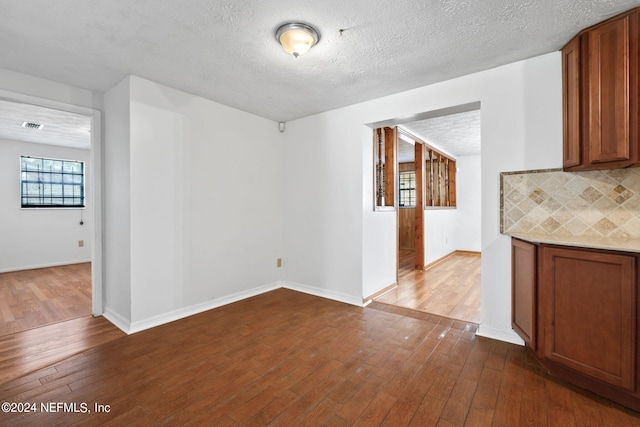 unfurnished dining area with a textured ceiling and dark hardwood / wood-style flooring