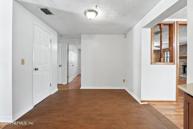 hall with a textured ceiling and wood-type flooring