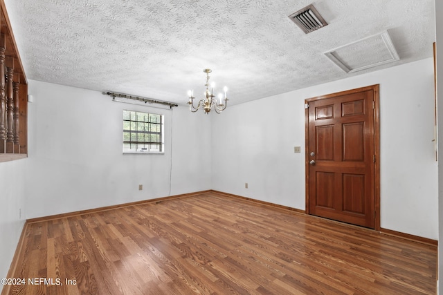 spare room with hardwood / wood-style flooring, a notable chandelier, and a textured ceiling