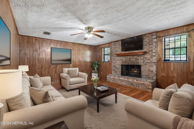 living room featuring a wealth of natural light, wooden walls, and hardwood / wood-style floors