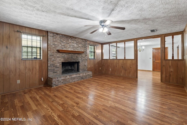 unfurnished living room featuring a fireplace, wood walls, and wood-type flooring