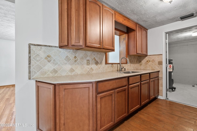 kitchen with sink, wood-type flooring, and a textured ceiling