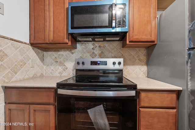 kitchen with tasteful backsplash, appliances with stainless steel finishes, and light stone countertops