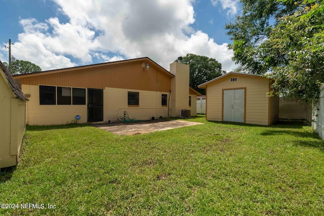 back of house with a storage shed, a patio, central AC, and a yard