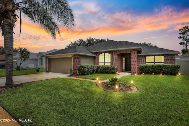 ranch-style home featuring brick siding, roof with shingles, a lawn, an attached garage, and driveway