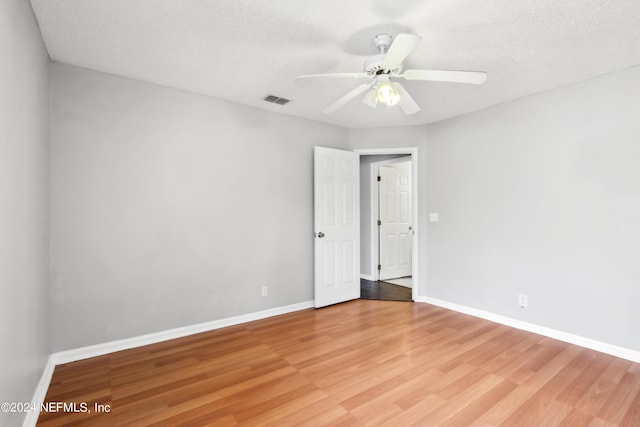 spare room featuring ceiling fan, light wood-type flooring, visible vents, and baseboards