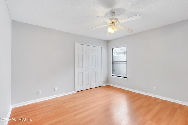 unfurnished bedroom with a textured ceiling, a closet, light wood-style flooring, and baseboards