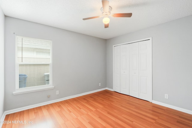 unfurnished bedroom featuring baseboards, a closet, a textured ceiling, and light wood-style floors