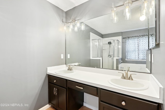 full bathroom with double vanity, a stall shower, and a sink