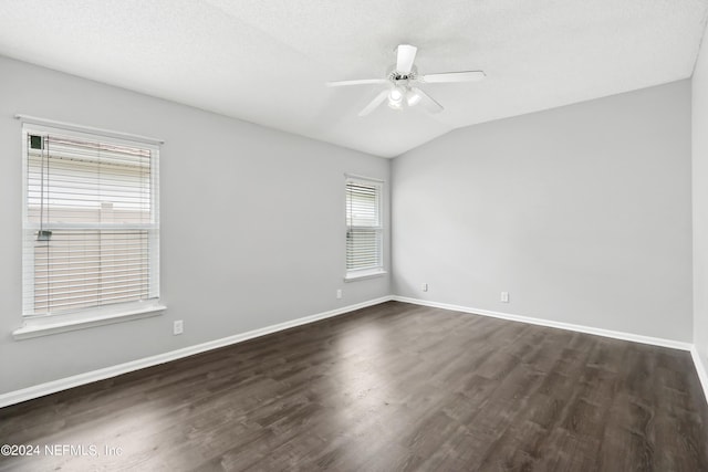 empty room with baseboards, dark wood finished floors, a ceiling fan, vaulted ceiling, and a textured ceiling