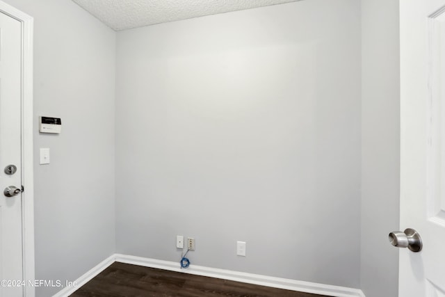 laundry area with a textured ceiling, dark wood-type flooring, and baseboards